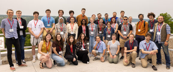 REU Students standing on a rooftop patio overlooking a a campus